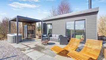 Un espace de vie extérieur moderne comprenant un jacuzzi, des sièges et une pergola.