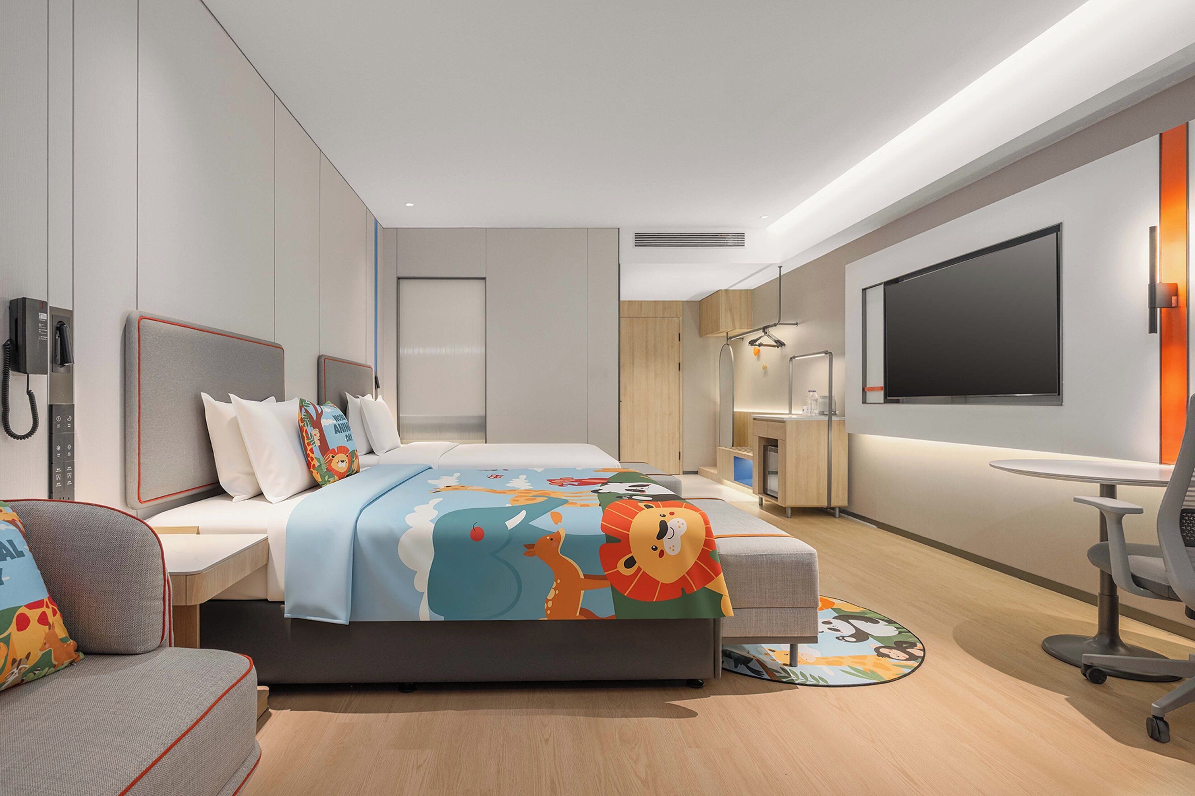 Ein modernes Hotelzimmer mit Bett, Schreibtisch, Stuhl, Fernseher und Telefon.