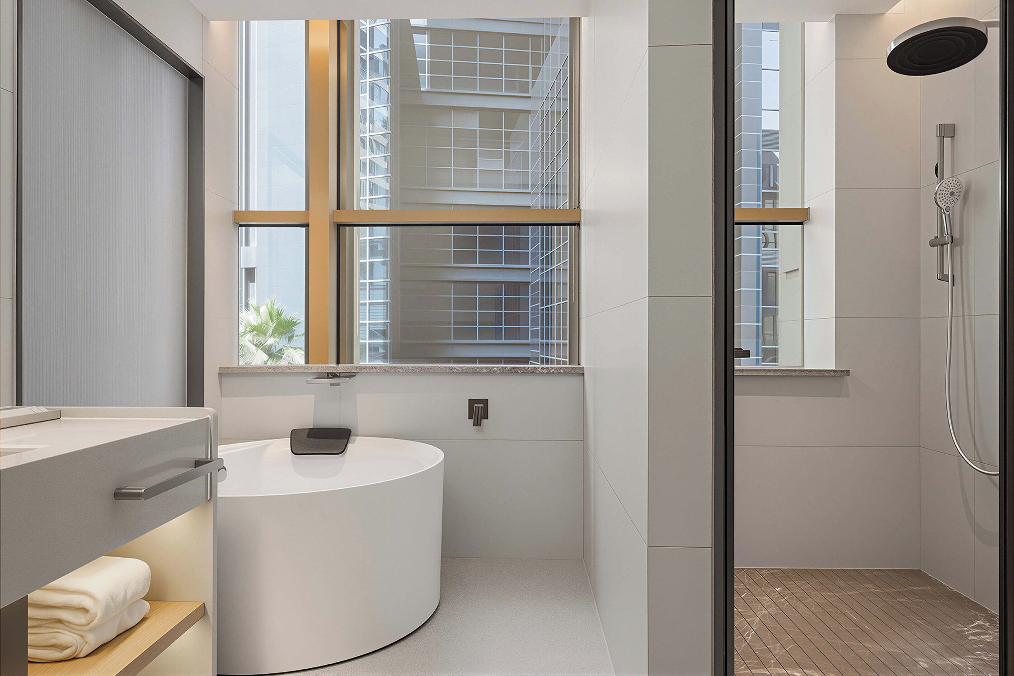 A modern bathroom with a round sink, a window, and a shower area.
