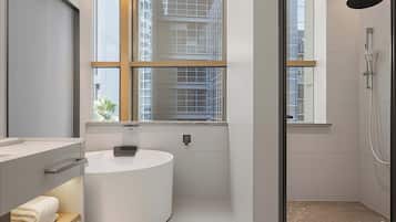 A modern bathroom with a round sink, a window, and a shower area.