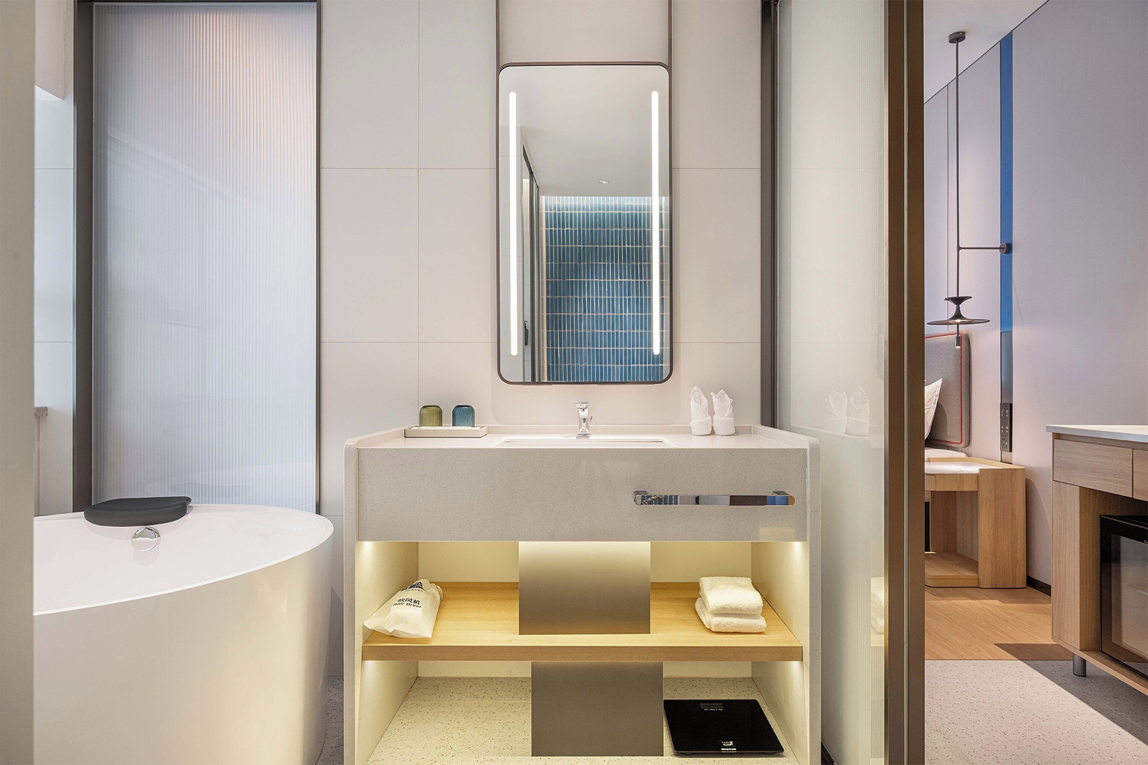 A modern bathroom with a white sink, a mirror, and a towel rack.