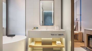 A modern bathroom with a white sink, a mirror, and a towel rack.