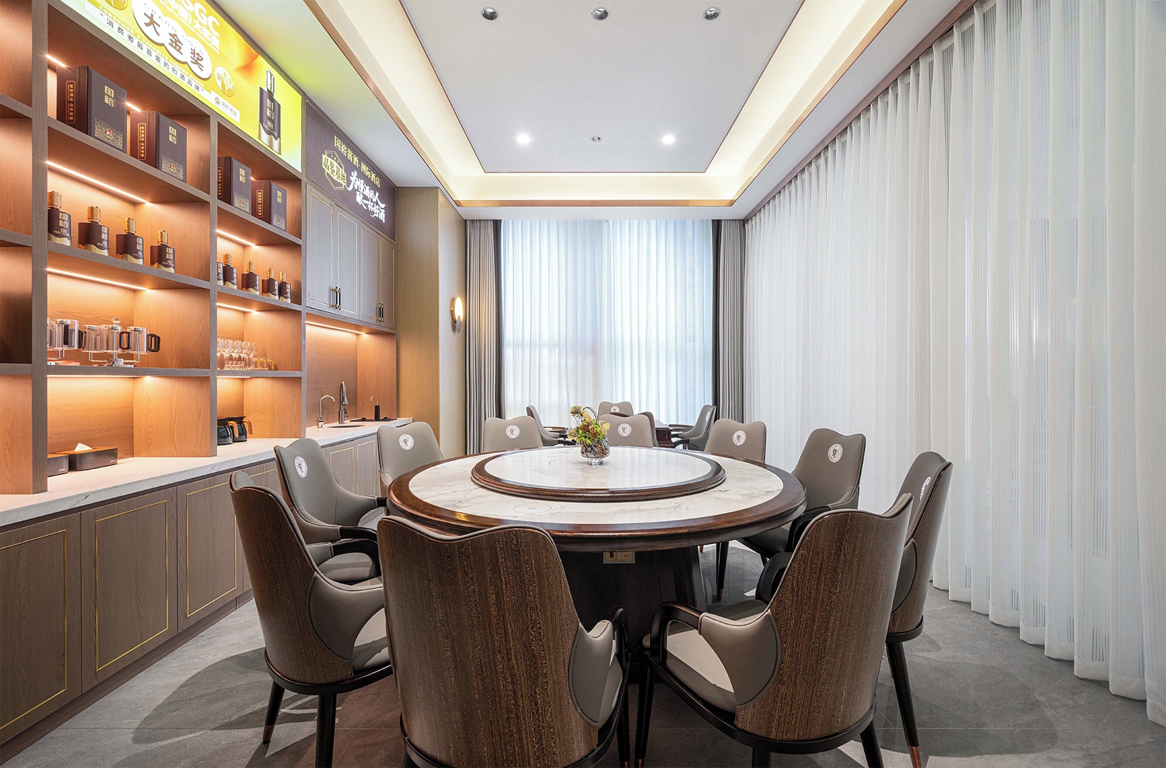 A modern conference room with a round table, comfortable chairs, and a shelf with various items.