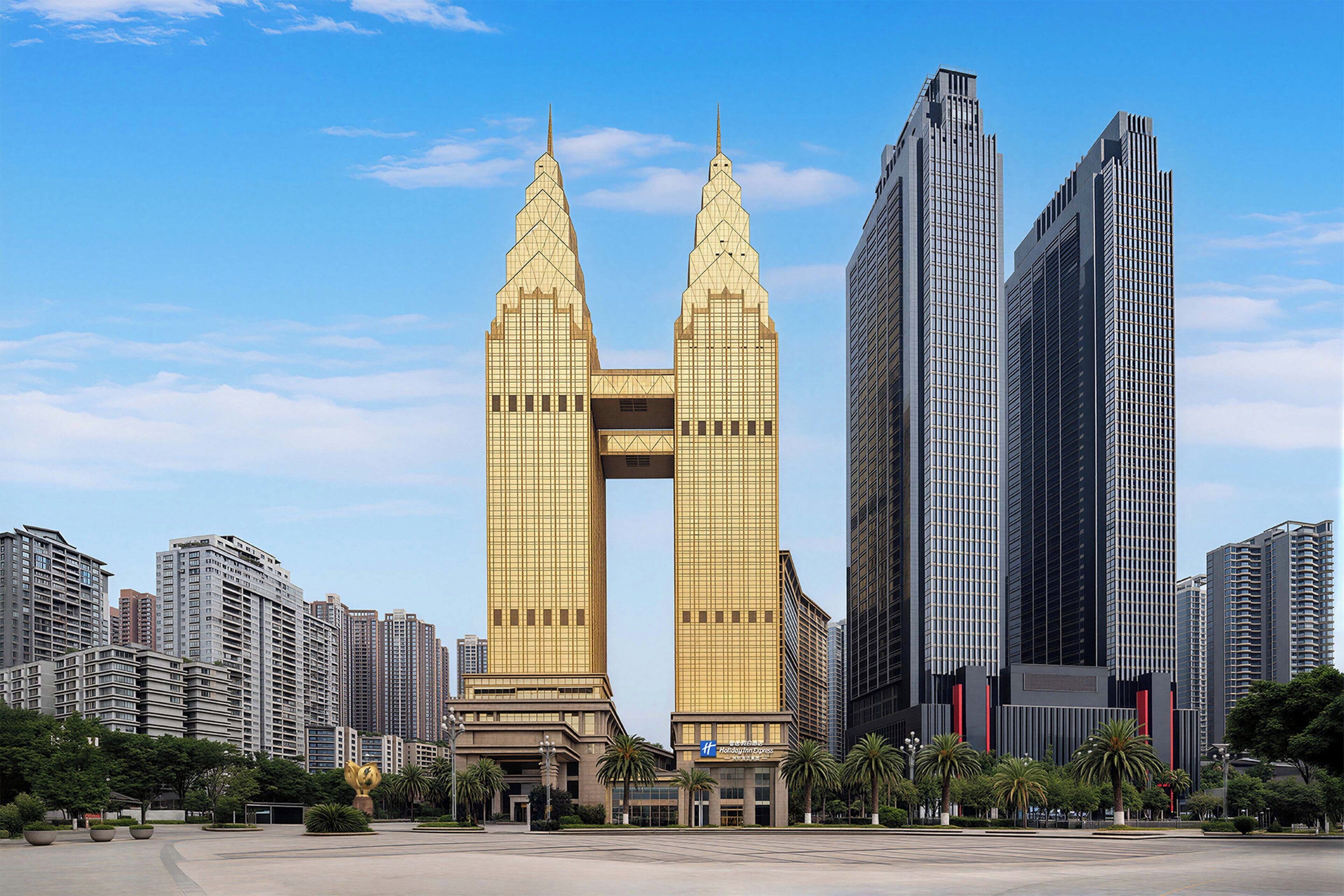 Un moderno rascacielos de diseño con dos torres gemelas distintivas, rodeado de otros edificios altos en un entorno urbano.