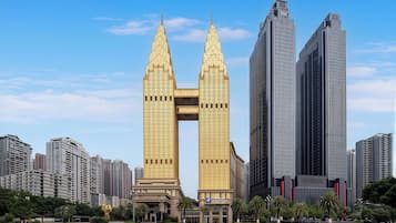 A modern high-rise building with a distinctive twin spire design, surrounded by other high-rise buildings in an urban setting.