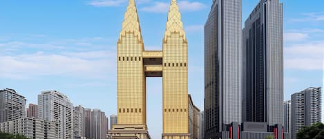 A modern high-rise building with a distinctive twin spire design, surrounded by other high-rise buildings in an urban setting.
