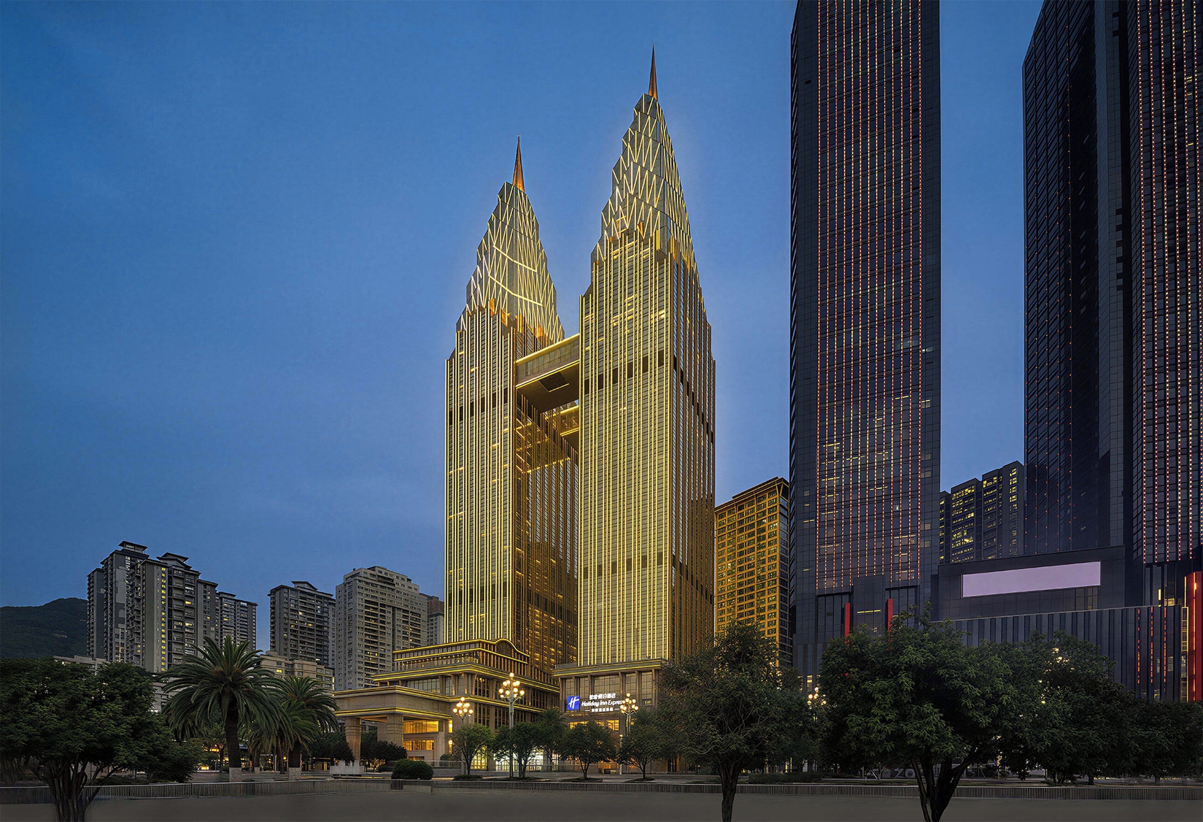 A high-rise hotel with a distinctive twin spire design, surrounded by other modern buildings.