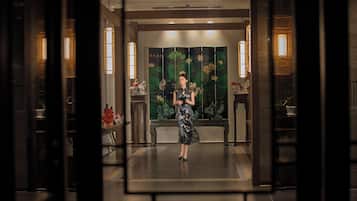 A woman standing in a lobby with a traditional backdrop, a bench, and decorative lighting.