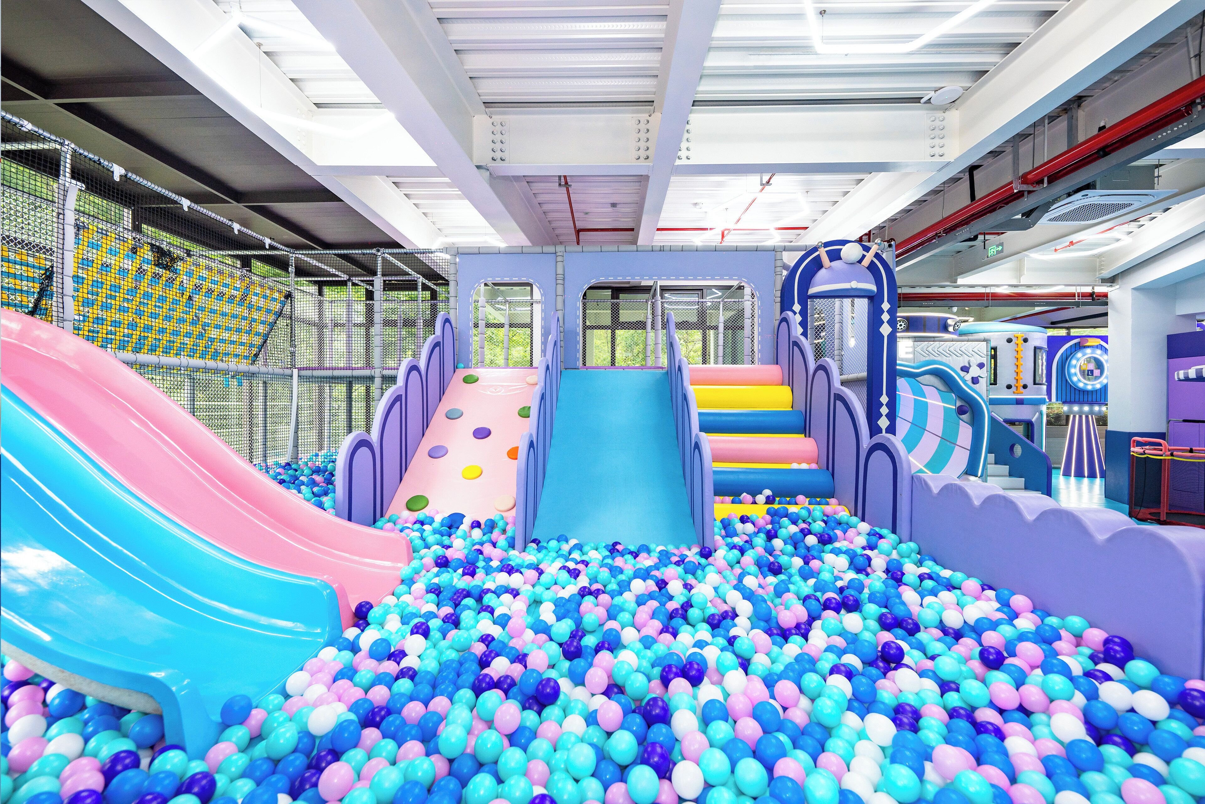 Un área de juegos interior con toboganes, piscina de pelotas y estructuras para escalar.