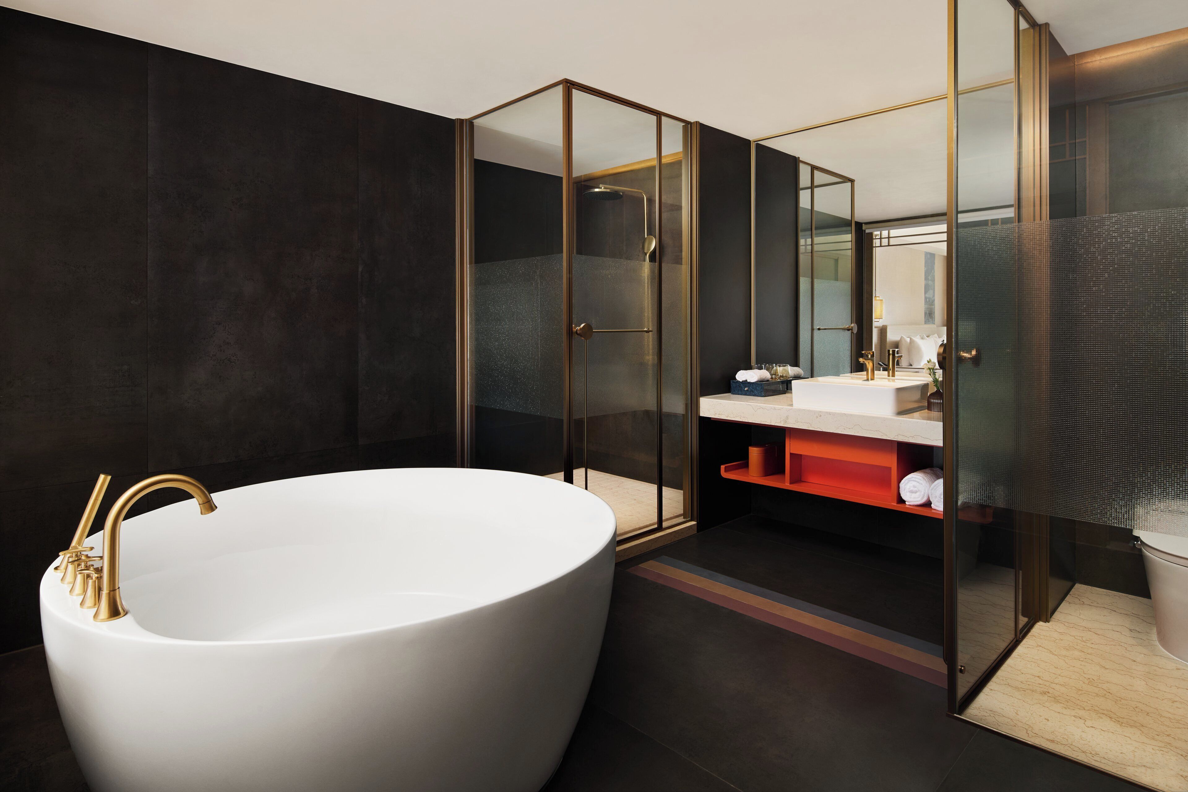 Un baño moderno con una bañera independiente, ducha con mampara de vidrio y tocador con espejo.