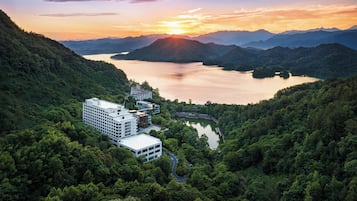 Un hotel moderno con varias edificaciones, rodeado de abundante vegetación y un lago.