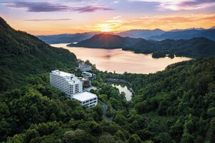 Un hotel moderno con varias edificaciones, rodeado de abundante vegetación y un lago.