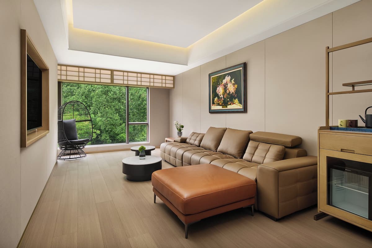 A modern living room with a sectional sofa, a black chair, a small round table, and a cabinet with a glass door.