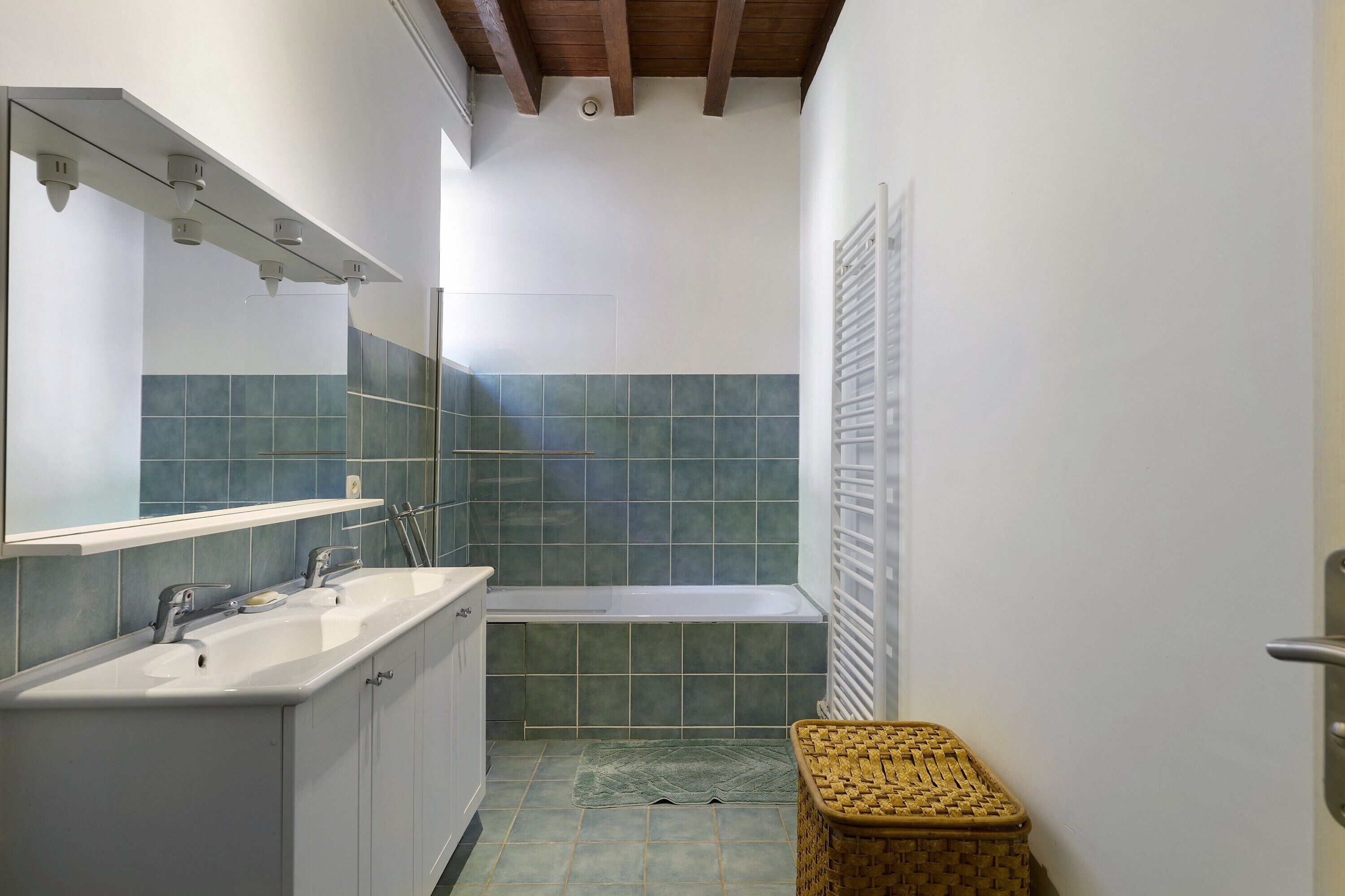 A bathroom with a sink, mirror, and bathtub.