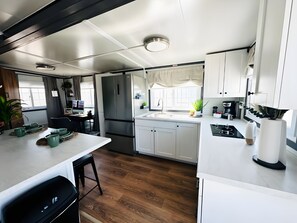 A modern kitchen with a central island, a built-in stove, and a refrigerator. - Private Studio Suite with Queen and Office, Full Kitchen and In-Unit Laundry (Pecos)