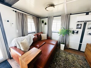 A modern living room with a brown leather sofa, a wooden coffee table, and a patterned rug.