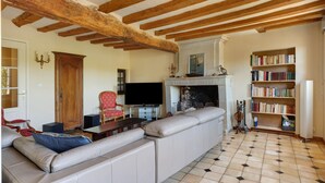 A living room with a large sectional sofa, a fireplace, a bookshelf, and a television.