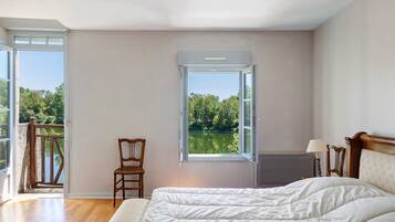 Una camera da letto con un letto, una sedia, una finestra vista lago e un balcone.
