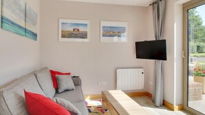 A modern living room with a sofa, a bench, a flat-screen TV, and two framed pictures on the wall. - 1 Bed in Tenterden (oc-79130) (Tenterden)