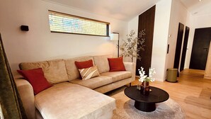 Uma sala de estar moderna com um sofá, uma mesa de centro e uma janela com persianas.