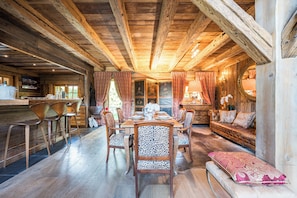 A wooden interior with a dining table, chairs, a sofa, and a bench. - Chalet Zibeline (Megève)