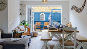 A modern living room with a dining area, a large window, and a blue exterior wall. - 4 Bed in Broadstairs (oc-81104) (Broadstairs)