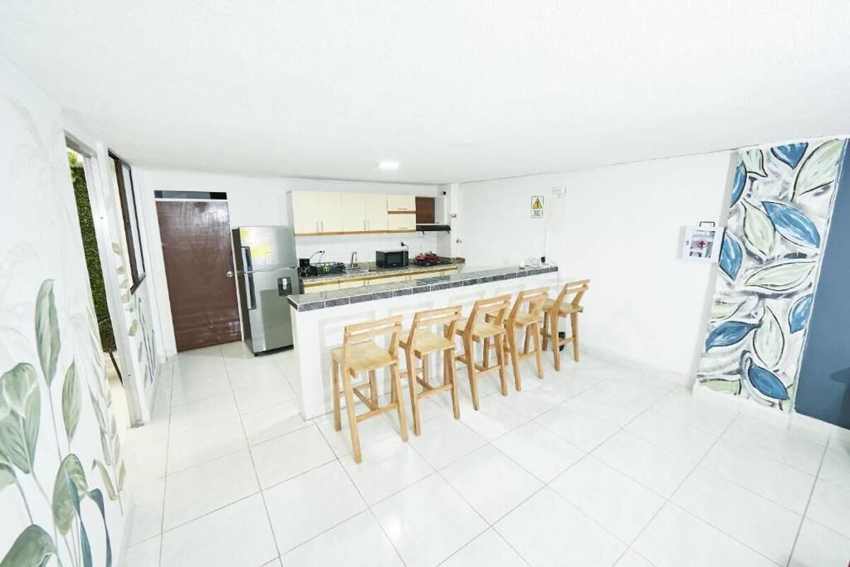 A modern kitchen with white cabinets, a central island with bar stools, and a refrigerator.