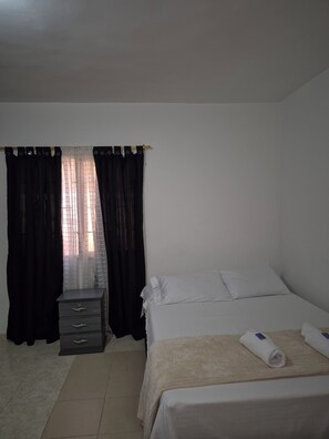 A bedroom with a bed, a dresser, and a window with curtains. - Hostel Casa Host 72 (Medellín)