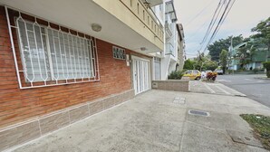 Un edificio con fachada de ladrillo, amplias ventanas con rejas y una entrada protegida por una reja.