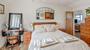Une chambre à coucher comprenant un lit, des tables de chevet, un bureau, un miroir et une armoire.