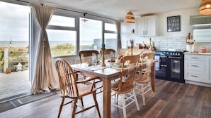 Une cuisine spacieuse avec une grande table à manger, des chaises en bois et une vue sur la mer.