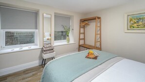 Quarto com cama, cadeira, janela com persianas, escada de madeira e um quadro na parede.