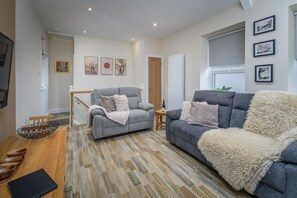 A living room with a grey sofa, a grey armchair, a wooden coffee table, and a patterned rug. - 2 Bed in Morpeth (oc-coq143) (Morpeth)