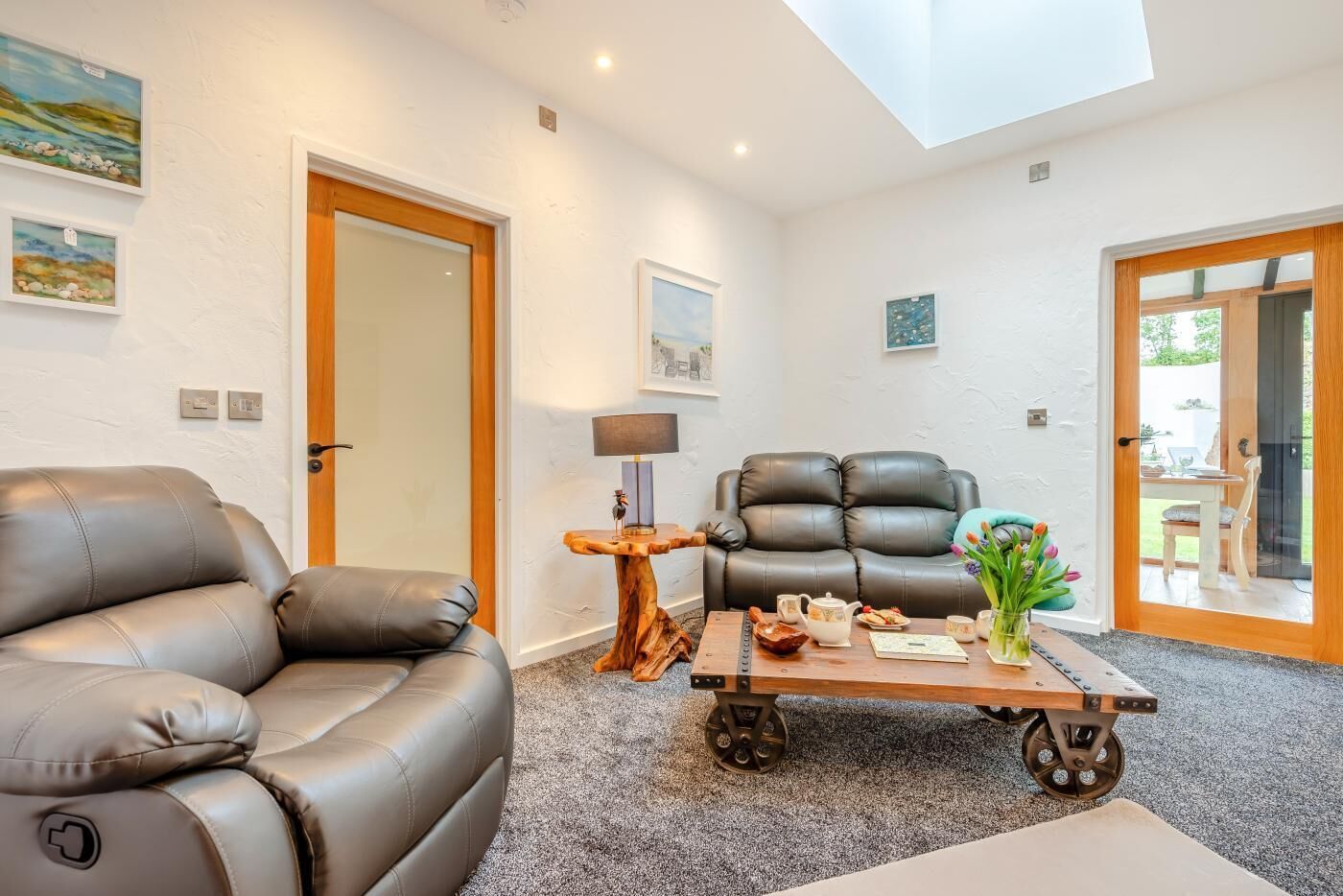 A modern living room with a leather sofa, a wooden coffee table, and a dining area with a table and chairs.