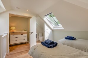 A bedroom with two beds, a nightstand, a lamp, a window, and a door leading to a bathroom. - 2 Bed in Waldron (oc-v33536) (Foxhunt Green)