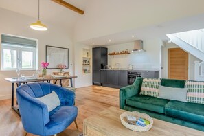 A modern living room with a blue chair, a green sofa, and a dining area with a table set for two. - 2 Bed in Waldron (oc-v33536) (Foxhunt Green)