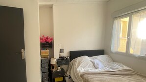 Une chambre à coucher avec un lit, une table de chevet, une commode, une fenêtre et une porte.