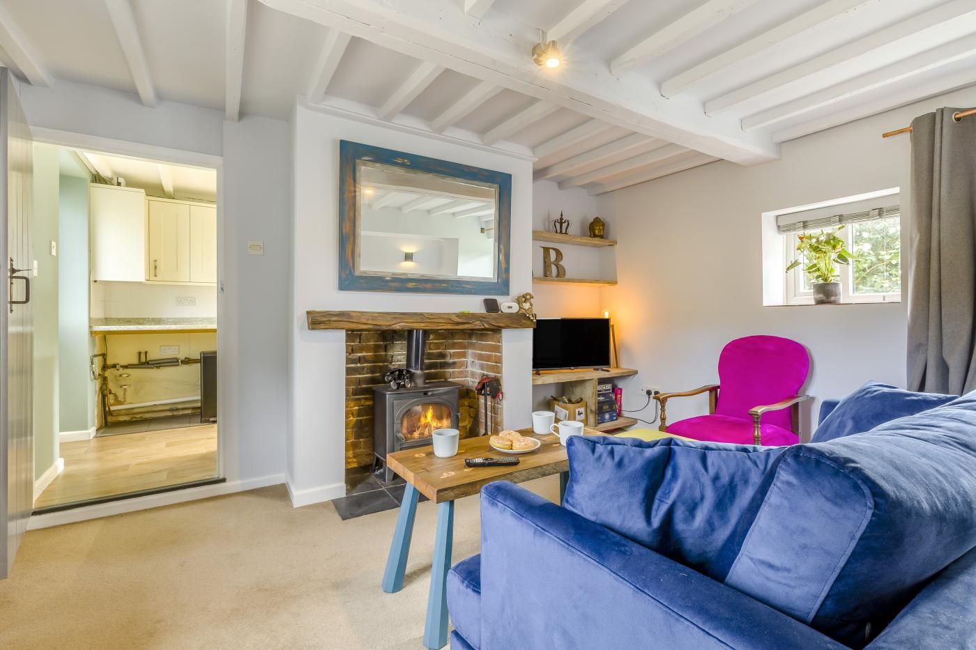 A cozy living room with a fireplace, a television, and a bright pink chair.