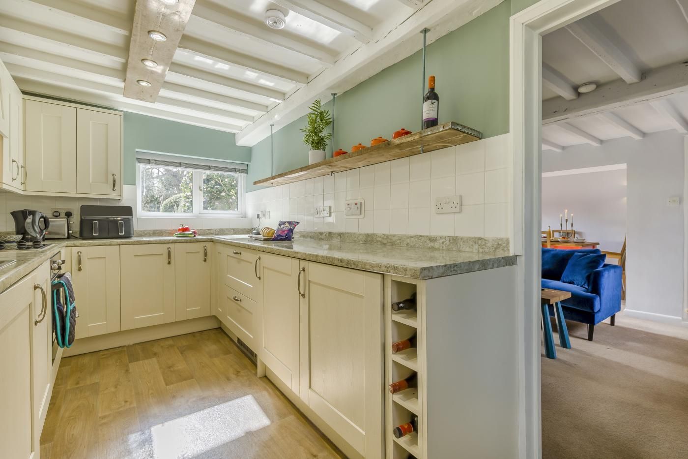 Una cocina con armarios blancos, encimera de madera y ventana.
