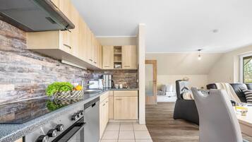Eine moderne Küche mit Holzschränken, einem eingebauten Backofen und einer Arbeitsplatte mit Wasserkocher und Kaffeemaschine.