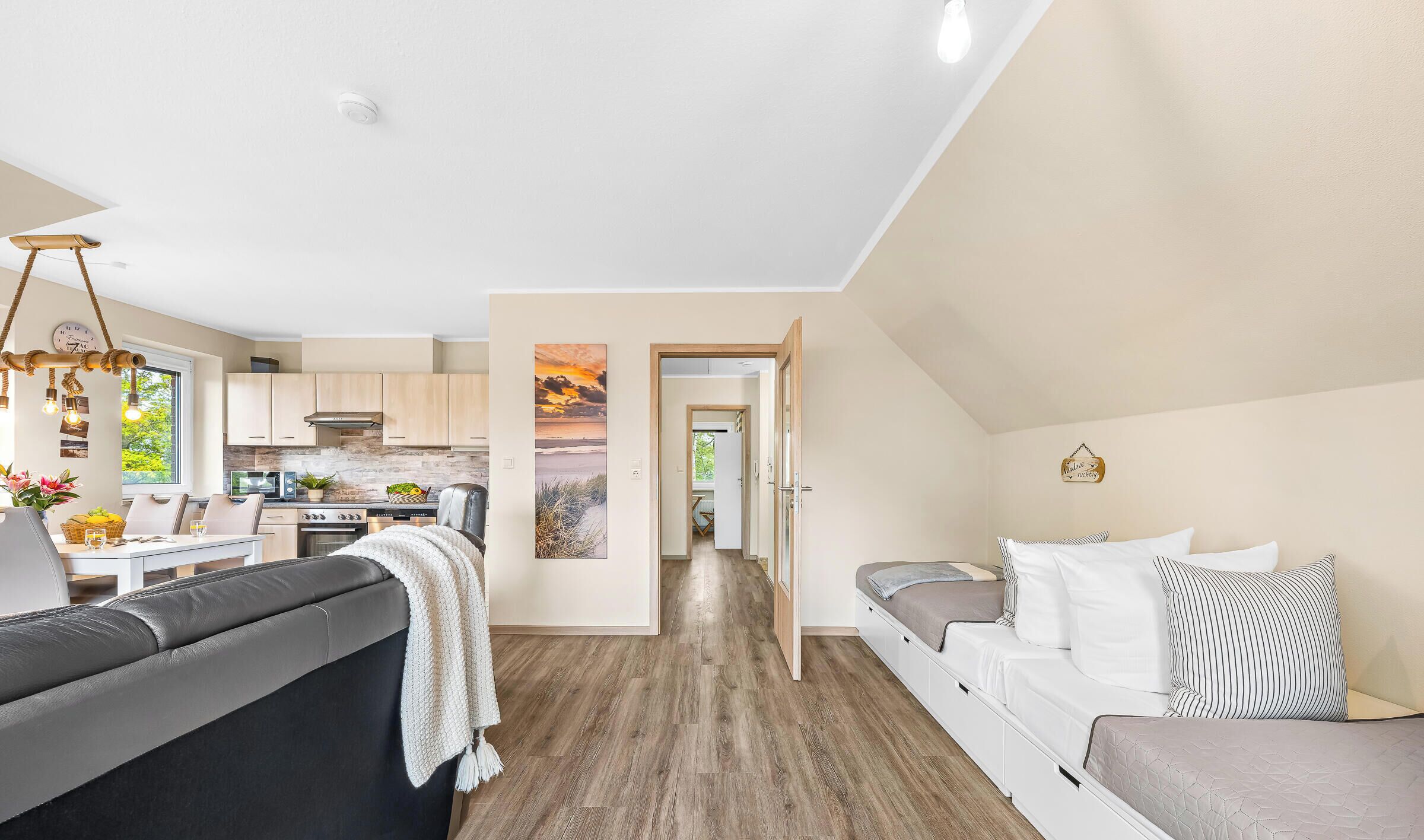 Ein modernes Interieur mit Essbereich, Küche und Wohnzimmer, inklusive Sofa und Kissen.