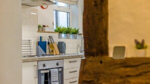 Une cuisine avec des carreaux blancs, une cuisinière, un évier et une fenêtre.