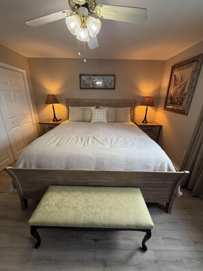 A bedroom with a bed, two bedside lamps, a ceiling fan, a bench, and artwork on the walls. - 1BR/1BA condo in Pensacola near Perdido Key, sleeps 4. (Perdido Key)