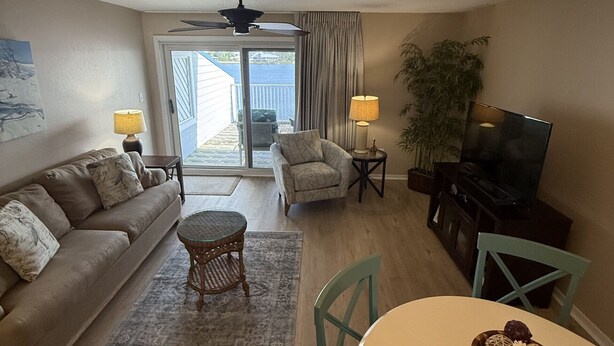 A living room with a sofa, a dining table, a ceiling fan, and a television. - D 32 Sundown Condominiums (Perdido Key)