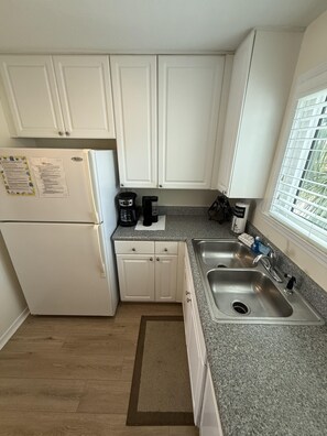 A compact kitchen with white cabinets, a stainless steel sink, and a coffee maker. - 1BR/1BA condo in Pensacola near Perdido Key, sleeps 4. (Perdido Key)