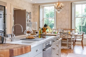 Eine moderne Küche mit Marmorarbeitsplatte, eingebautem Backofen und einem Essbereich mit Holztisch und Stühlen.