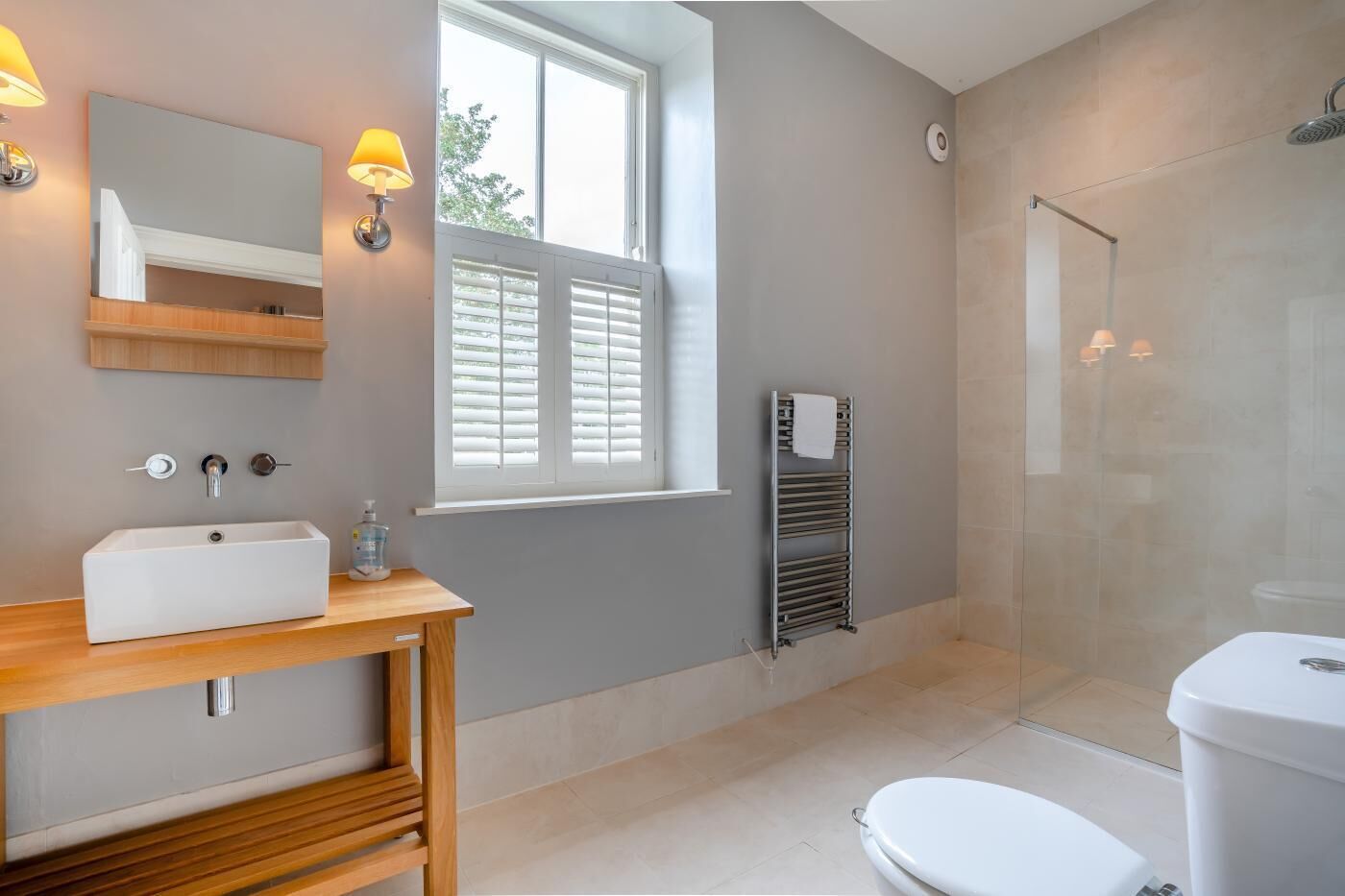 Un baño moderno con lavamanos, espejo y ducha.