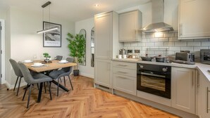 Eine moderne Küche mit grauen Schränken, einem Holztisch und einem Fischgrätparkett.
