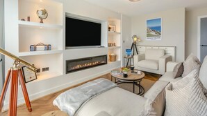 Ein modernes Hotelzimmer mit Flachbildfernseher, Kamin, Teleskop, Hinweisschild für Gästezimmer und einem Blickfang-Poster.
