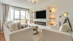 Ein Wohnzimmer mit Kamin, Flachbildfernseher und Bücherregal.